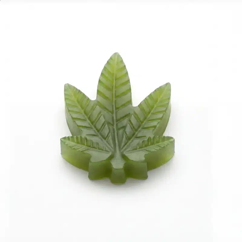 Single green cannabis leaf shaped THC gummy close-up with glossy finish